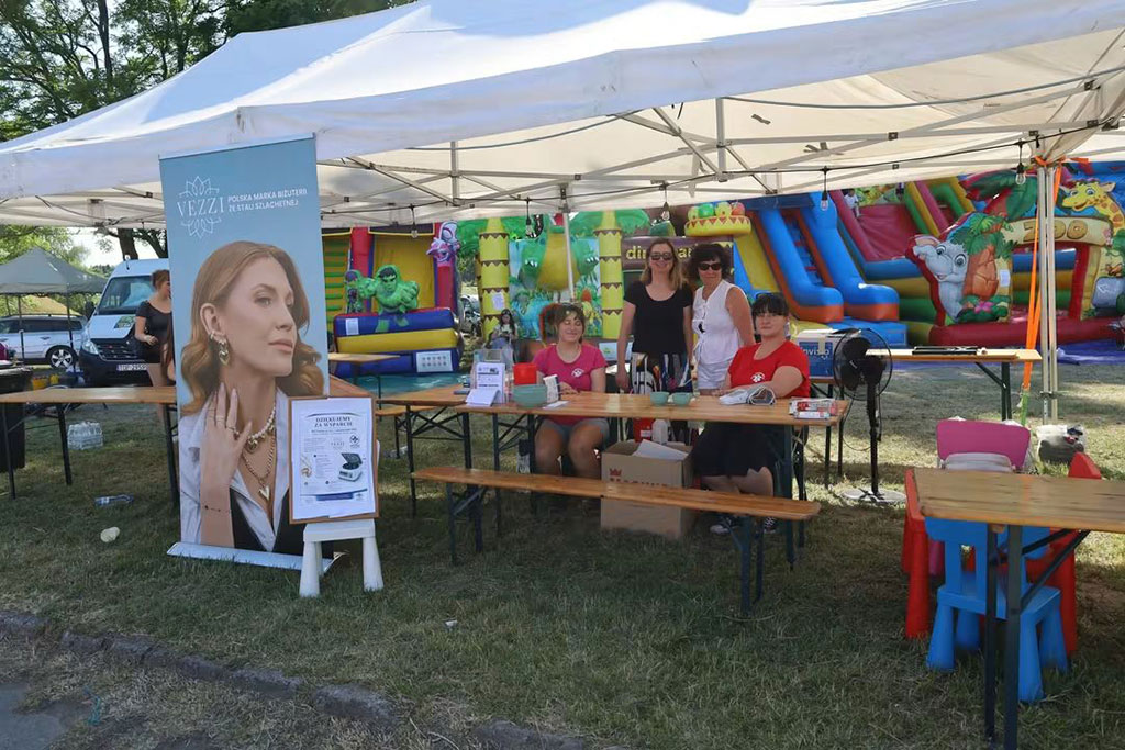 Stoisko SPZOZ pod białym namiotem podczas Dni Ożarowa, ze stanowiskami badań i planszą VEZZI.